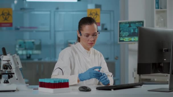 Mujer científica analizando líquido en tubo de ensayo y utilizando computadora — Vídeos de Stock