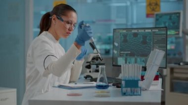 Kadın biyolog deney tüpü ve beher ile mikro pipet kullanıyor.