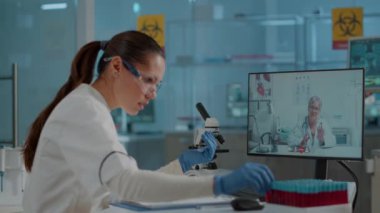 Bilim adamı laboratuvarda video konferansı uzmanı ile konuşuyor.
