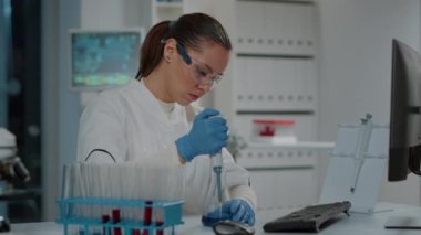 Laboratuvar çalışanı deney tüpleri ve deney tüpleriyle mikro pipet kullanıyor.