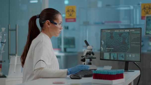 Химик в защитных очках и перчатках, работающий на компьютере — стоковое видео