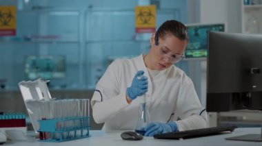 Bilim adamı deney tüpü ve deney tüpünde sıvı için mikro pipetle çalışıyor.