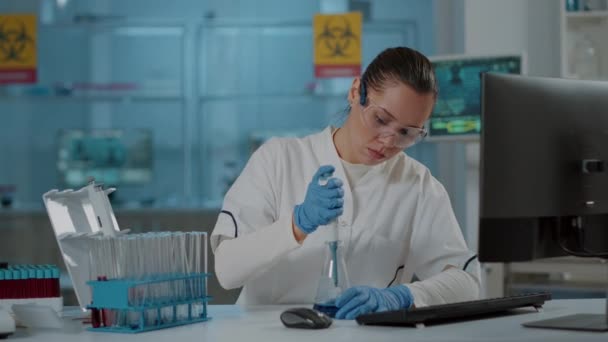 Wetenschapper werkt met micro pipet voor vloeistof in bekerglas en reageerbuis — Stockvideo