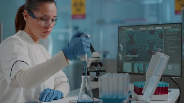 Chemik pracujący nad eksperymentem z mikropipetą i zlewką — Wideo stockowe