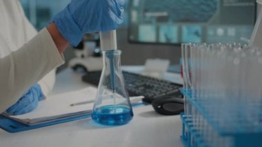 Bilim adamı, maddeyi mikro pipet ve beher ile karıştırıyor.