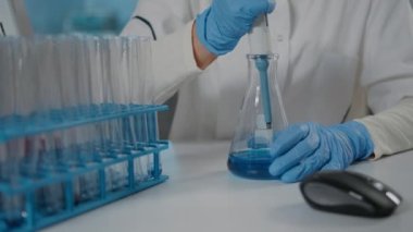 Biyolog deney tüpü ve deney tüpündeki maddeleri mikro pipetle karıştırıyor.