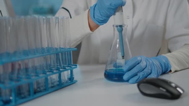 Biolog som bruker mikropipette til å blande stoff i begerglass og prøverør – stockvideo