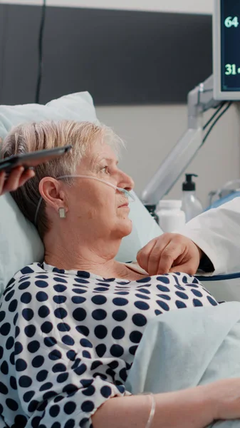 Medisch team doet checkup bezoek voor oudere patiënt in bed — Stockfoto