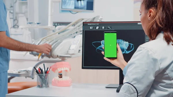 Dentiste tenant verticalement smartphone avec écran vert — Photo