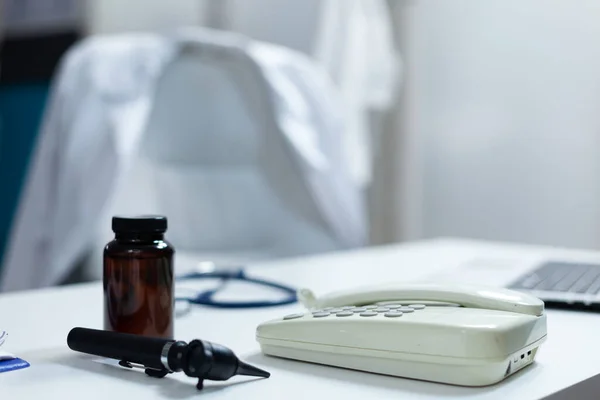 Closeup of medical otoscop and landine standing on table in empty doctor office — Stock Photo, Image