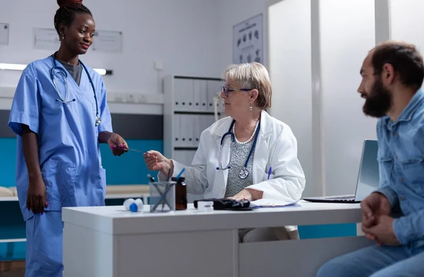 Afrykańska pielęgniarka daje wyniki radiografii do lekarza na spotkanie z mężczyzną — Zdjęcie stockowe