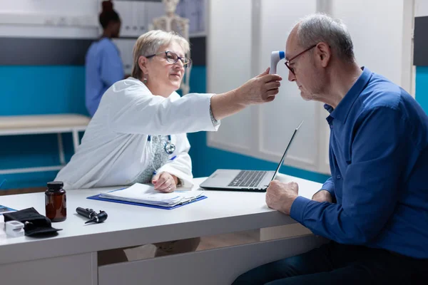 Especialista usando termómetro para medir la temperatura del hombre enfermo —  Fotos de Stock