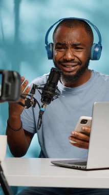 Vlog yazarı kamerada kötü haber okuyor ve elinde akıllı telefon tutuyor.