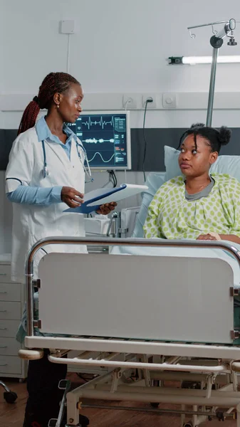 Afro-Amerikaanse arts doet overleg met patiënt in bed — Stockfoto