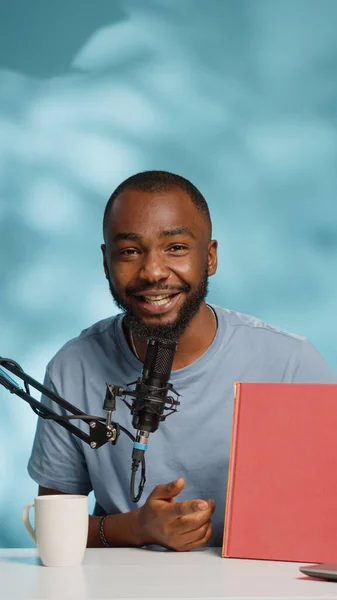 El bloguero negro sostiene el libro para revisar el producto en la cámara para vlog —  Fotos de Stock