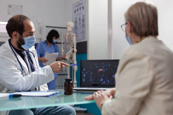 Doctor pointing at coronavirus presentation to show bacteria on display — 图库照片