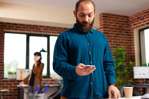 Empresário segurando smartphone moderno à espera de chamada imporante olhando para o tempo do relógio — Fotografia de Stock