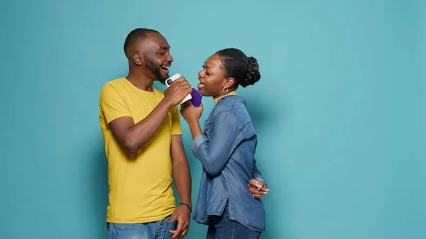 Playful couple singing song and using smartphone as microphone — Foto Stock