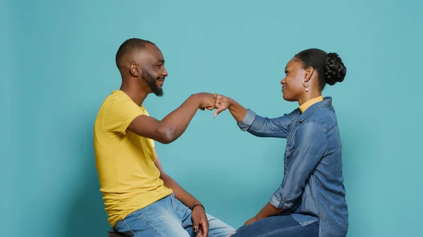 Couple sitting in studio and bumping fists together to show support and respect — Stockfoto