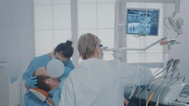 Hemşire ve stomatolog, sondaj aletlerini kullanarak taşıyıcıları çıkarıyorlar.