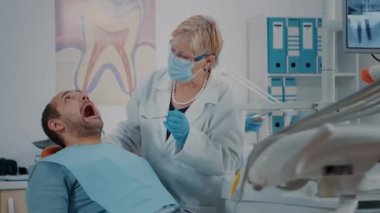 Diş muayenesi için diş aletlerini kullanan ağızcı doktor.