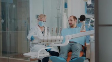 Kıdemli dişçi danışma için diş aletleri hazırlıyor