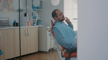 Diş ağrısı olan hasta diş hekimindeki dişçiye ağrıyı açıklıyor.