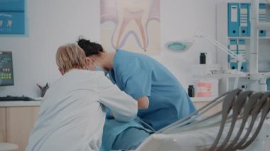 Hasta üzerinde oral bakım prosedürü yapan dişçi ve asistan