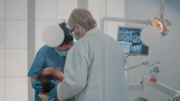 Stomatologist and nurse doing extraction procedure on patient — Vídeo de Stock