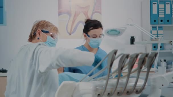 Verpleegkundige en stomatoloog die tanden van de patiënt onderzoekt — Stockvideo