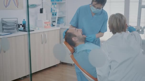 Estomatologista e enfermeiro usando ferramentas odontológicas para examinar o trabalho de dentição — Vídeo de Stock