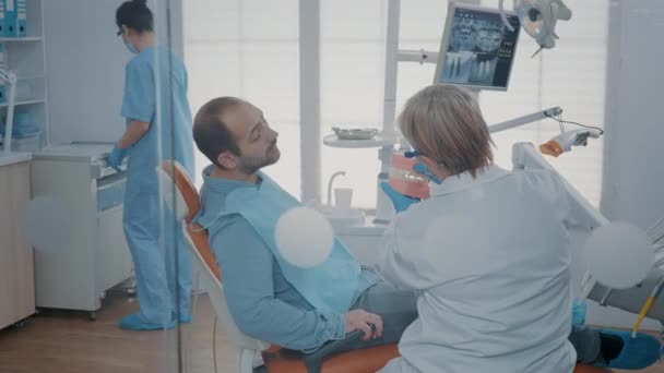 Стоматолог дает пациенту урок гигиены для правильной чистки зубов — стоковое видео