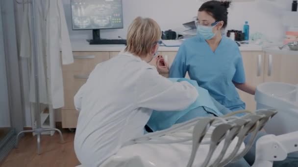 Equipe de especialistas fazendo procedimento de broca no paciente com dor de dente — Vídeo de Stock