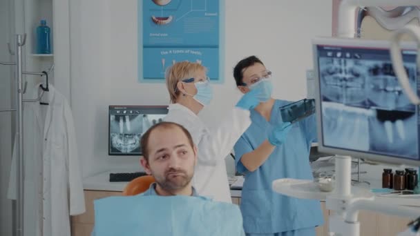 Senior tandarts en verpleegkundige analyseren x ray scan om diagnose te vinden — Stockvideo