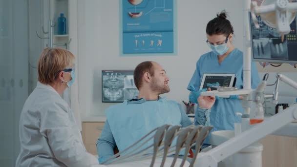 Equipo de odontología explicando radiografía al paciente enfermo — Vídeos de Stock