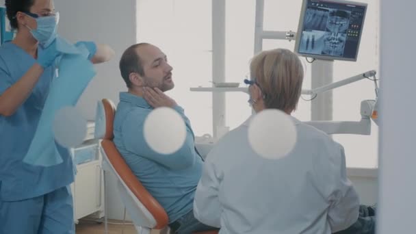 Dentiste montrant radiographie dentaire au patient sur chaise dentaire — Video