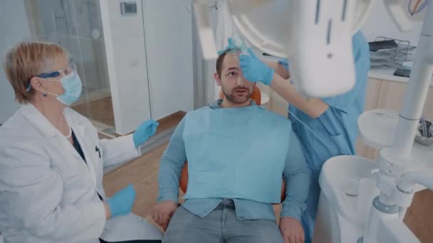 Equipo de especialistas haciendo anestesia en el paciente en consultorio de odontología — Vídeo de stock