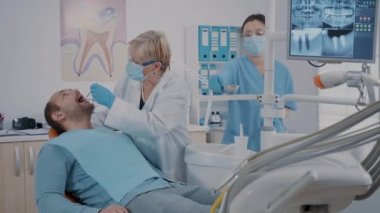 Kıdemli dişçi danışmanlık için diş aletleri ve aletler kullanıyor