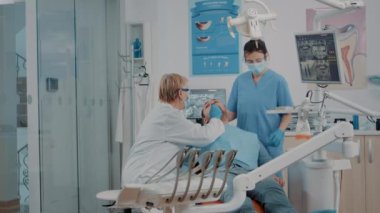 Diş hekimi ve hemşire, dişçi dolabındaki hastaların dişlerini inceliyor.