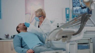 Ağzı açık hasta dişçiden muayene oluyor.