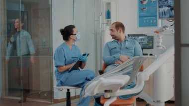Diş hemşiresi not alıyor ve diş ağrısı olan hastaya danışıyor.