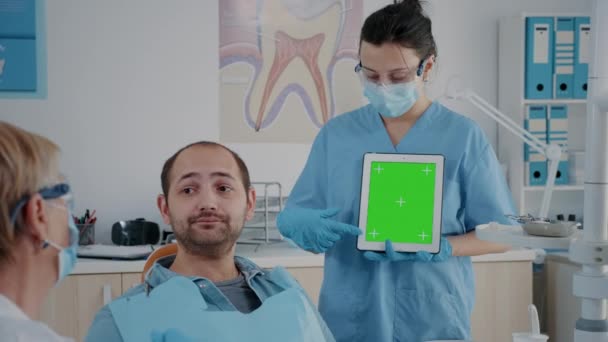 Assistent verticaal houden van digitale tablet met groen scherm — Stockvideo