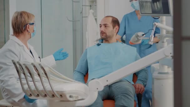 Stomatoloog toont röntgenscan diagnose aan patiënt — Stockvideo