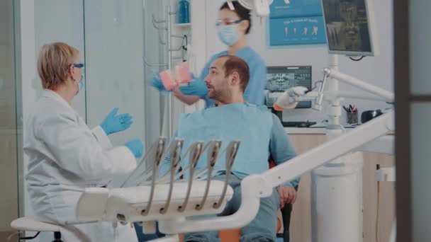歯ブラシで入れ歯をきれいにする正しい方法を示す歯科医 — ストック動画