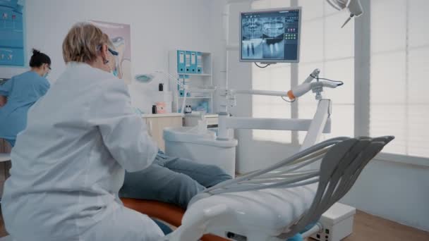 Orthodontist wijst naar tandenradiografie op monitor — Stockvideo