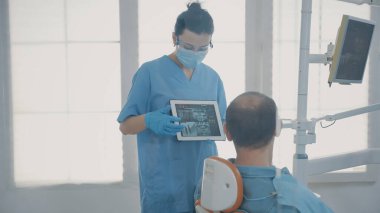 Diş hekimi asistanı diş röntgeniyle dijital tablet tutuyor.