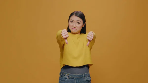 Displeased woman showing thumbs down on camera in studio — 图库照片