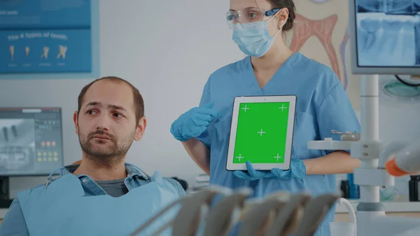 Стоматология медсестра вертикально держит планшет с зеленым экраном — стоковое фото