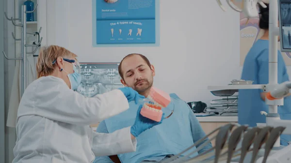 Стоматолог использует искусственную челюсть, чтобы объяснить, как правильно чистить зубы — стоковое фото