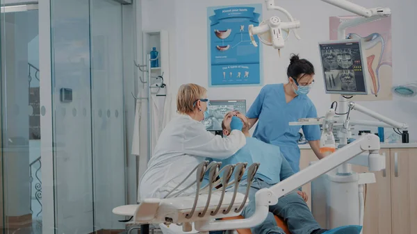 Tandarts en verpleegkundige onderzoeken tanden van de patiënt in de tandheelkunde kabinet — Stockfoto